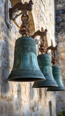 Fototapeta premium Ornate bronze church bells hanging on stone wall
