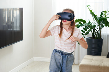 Teenage girl wearing virtual reality goggles headset and playing, vr box. technology, new generation, progress concept. Girl trying to touch objects in virtual reality.