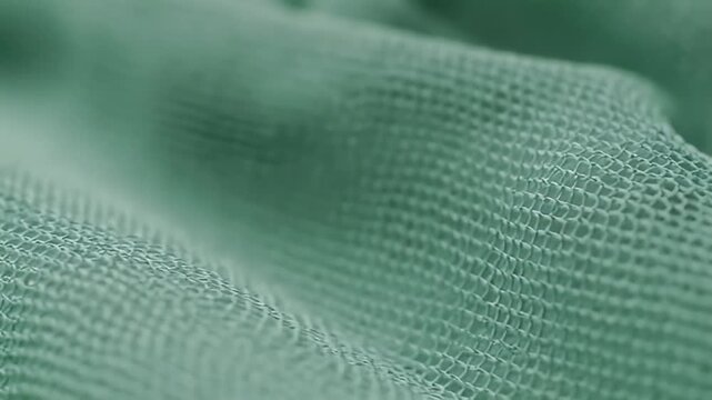Macro Shot of Folded Soft Green Gauze Fabric Texture in Dim Studio Lighting