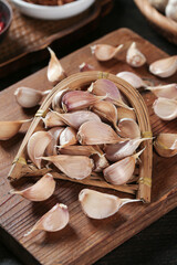 Freshly grown farm garlic cloves in rustic basket on wooden cutting board for cooking preparation