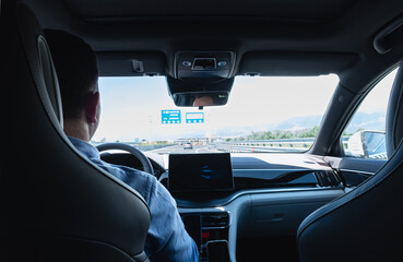 A male driver drives at speed through the highway of the city, a view from inside the car.