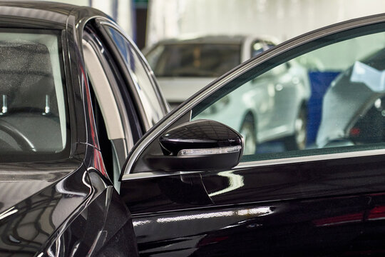Closeup shot of black modern car's side mirror in auto repair shop