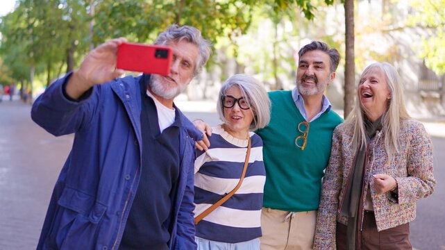 Happy senior friends taking a group selfie outdoors