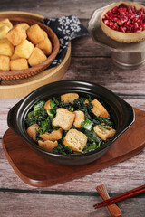 Traditional Asian fried tofu with green vegetables served in ceramic dishes on wooden table with chopsticks