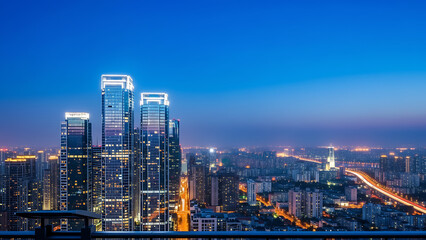 Fototapeta premium Cityscape view at night featuring illuminated skyscrapers and vibrant urban lights under a blue sky