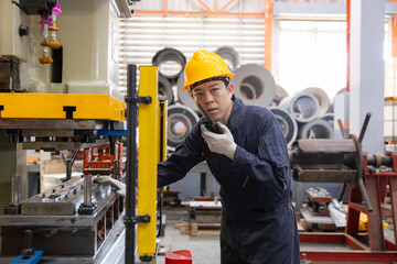 Industrial worker inspecting machinery with walkie-talkie