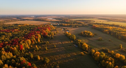 Aerial view of a vast landscape with autumnal colored trees and fields at sunrise