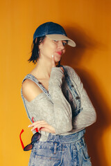 Playful Woman Posing in Denim Cap Against Orange Background