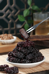 Xinjiang Black Dried Jujube Dates Chinese Healthy Fruit Snack on Plate with Fork