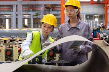 Female worker inspecting sheet metal with tablet