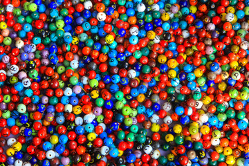 Colorful beads with randomly hand written style letters up for sale in the handicraft market in India.