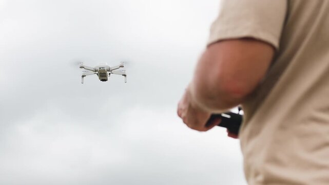 Drone development engineer tests new model in field. Tester deftly operates quadcopters remote control. Drone obeys engineers commands. Process of testing new drone model.