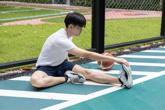Young Man Stretching on Basketball Court - Powered by Adobe