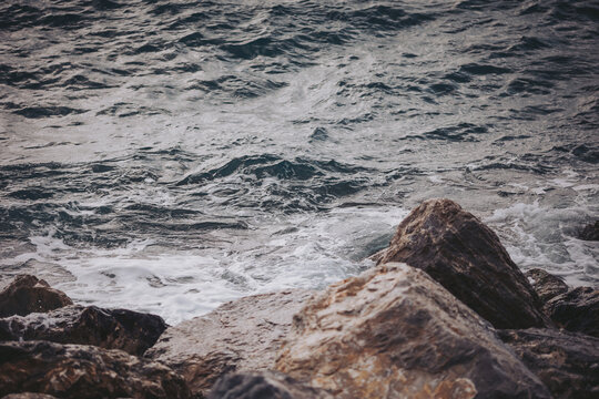 Waves crash against rocky shoreline at sunset with a tranquil atmosphere in a coastal location - Powered by Adobe