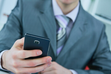 Young business man reading message with smartphone in office.