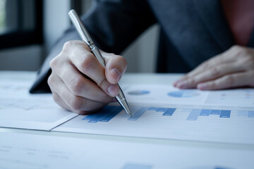 business professional analyzing financial charts with pen