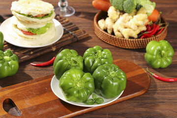 Fresh Green Bell Peppers and Colorful Vegetables on Rustic Wooden Kitchen Table