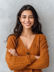Naklejka premium portrait of a young latin woman with pleasant smile and crossed arms isolated on grey wall with copy space beautiful girl with folded arms looking at camera against grey wall cheerful hispanic woman 