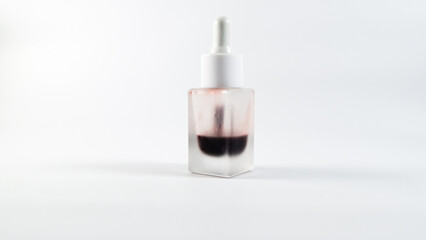Glass serum bottle with dual-tone liquid standing on a clean white background.