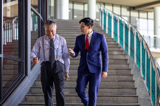 Meeting of two generations between senior and young business men at the company stairways sharing vision for their business development. Diversity and social inclusion in a business entrepreneurship - Powered by Adobe