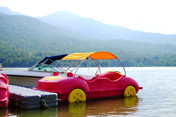 Pink pedal boats or water bikes and bicycles on kayak for rental in river in Thailand