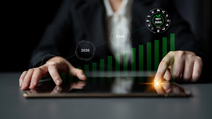 A businesswoman interacts with a tablet displaying a digital graph showcasing projected growth and net zero targets. The image highlights sustainability in finance. Gantry