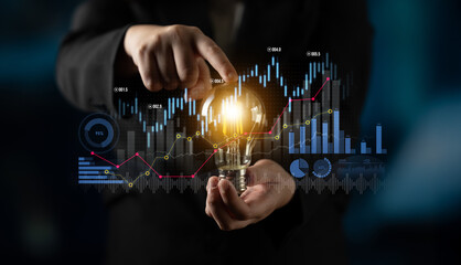A businessman presents a glowing lightbulb while surrounded by financial graphs and data, symbolizing innovation and growth in the modern economy. Scalp