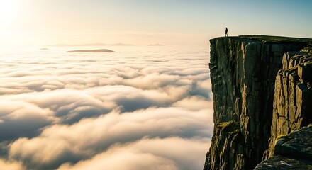 A lone figure stands atop a sheer cliff face overlooking a vast sea of golden clouds at sunrise or sunset Background image