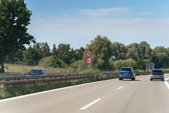 On the autobahn cars travel the A9 motorway at daytime, the traffic passing beneath a bright blue sky