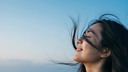 Asian woman looks up to sky, feeling hope and freedom in vast blue space