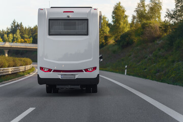 Road trip adventure awaits as a white recreational vehicle travels down a paved highway through scenic countryside