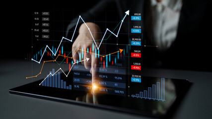 A business professional examines financial data on a tablet, showcasing market trends and insights...