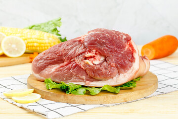 Raw Pork Knuckle with Fresh Vegetables and Lemon on Wooden Board