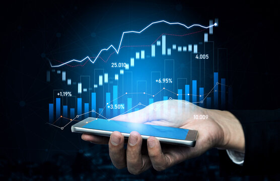 A hand holds a smartphone with a glowing display of financial graphs and data trends against a dark background, illustrating modern business analytics and technology use. Scalp