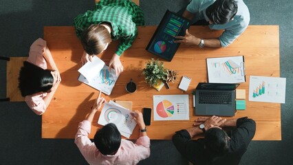 Top view of project manager using tablet to analyze data and financial chart while marketing team working together to brainstorm marketing campaign or planning strategy at meeting room. Convocation.