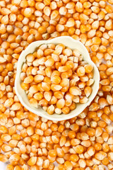 Raw Popcorn Kernels in Bowl on Corn Background