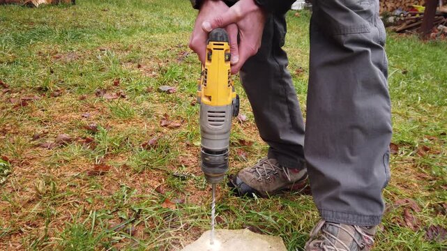 Hands of worker working on natural stone with cordless SDS rotary hammer drill 