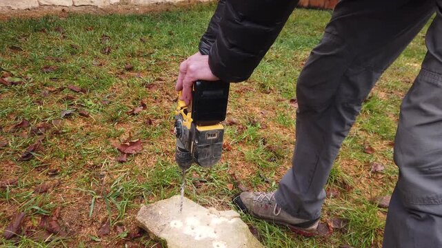 Hands of worker working on natural stone with cordless SDS rotary hammer drill 
