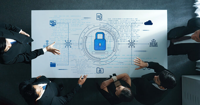 A diverse group of professionals works together at a table, discussing a cybersecurity strategy highlighted by digital data visualization and a prominent lock icon. Trope - Powered by Adobe