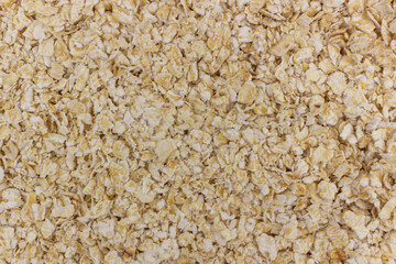 Full frame, close-up, and high-angle view of dry raw rolled oats or oatmeal flakes, covering the entire surface.