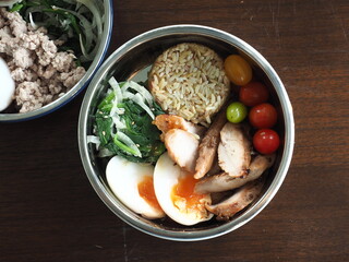 top view bowl of young brown rice with grilled chicken, boiled egg, spinach and onion salad and fresh cherry tomato