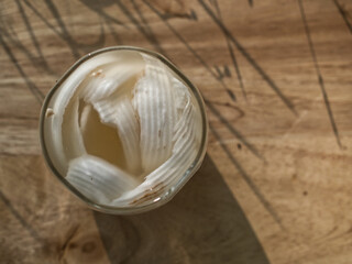 Coconut perfume water mixed with wild honey in a glass on a wooden floor in the grass warm morning light.