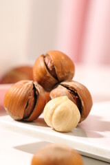 Hand-peeled hazelnuts with shells and nuts on white surface