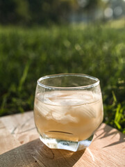 Coconut perfume water mixed with wild honey in a glass on a wooden floor in the grass warm morning light.