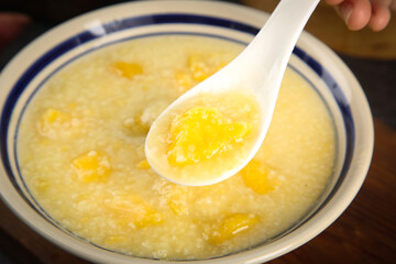 Sweet Yellow Millet Porridge with Potato Chunks - Healthy Breakfast Bowl with Wooden Spoon