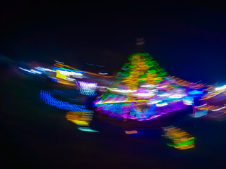 An abstract image of bright light particles moving in the darkness of the night, creating a dynamic colorful trail of blue, yellow, and green.