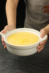 Chef Holding Bowl of Golden Yellow Porridge or Healthy Soup in Kitchen