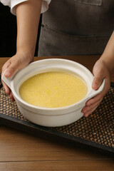 Hands holding bowl of creamy yellow porridge soup - healthy comfort food nutrition concept