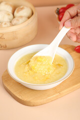 Healthy Yellow Millet Porridge Breakfast Bowl with Wooden Spoon and Fresh Vegetables