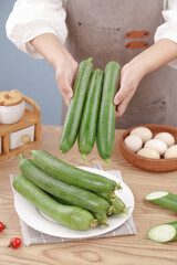 Chef Displaying Fresh Green Loofah Vegetables in Kitchen with Cooking Ingredients